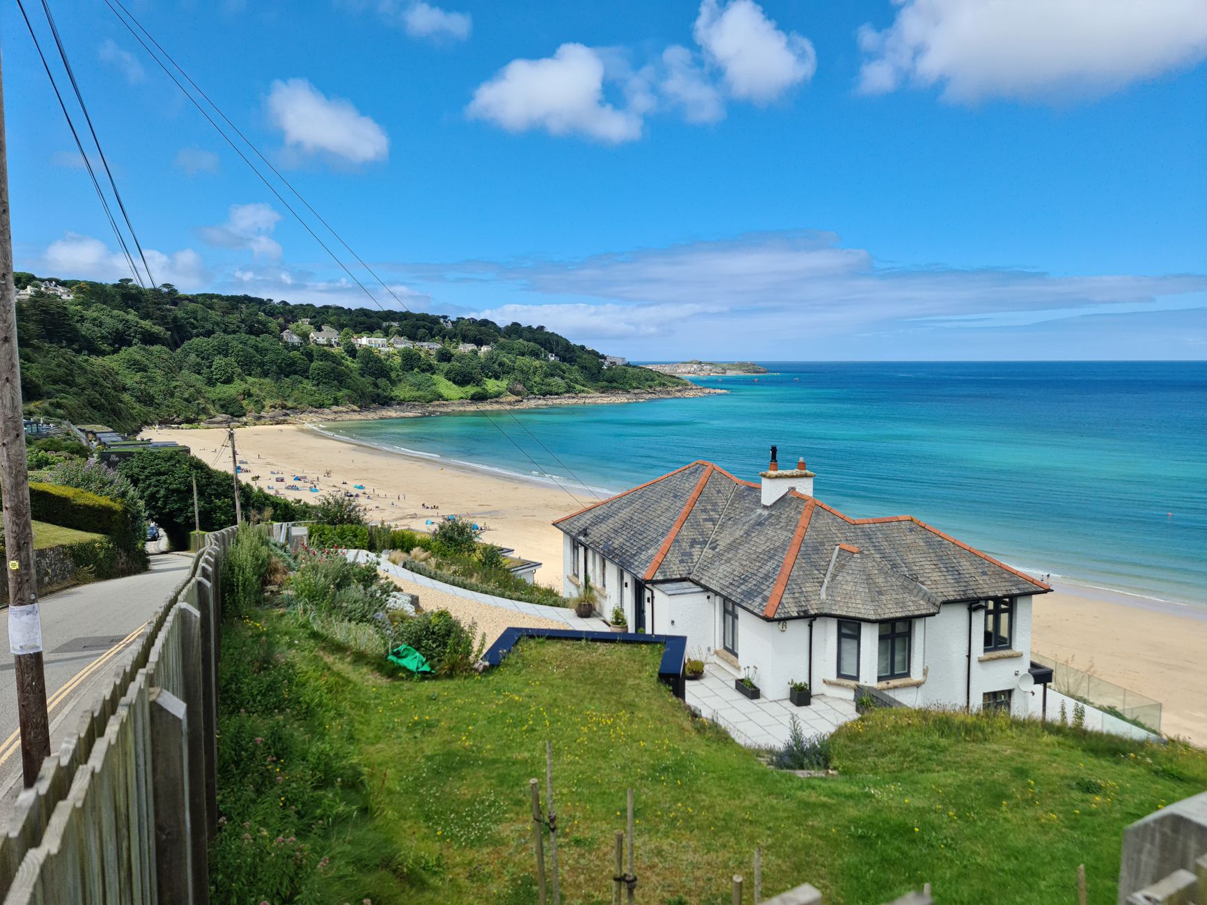 A white self-catering holiday cottage above a Cornish beach on the UK coast
